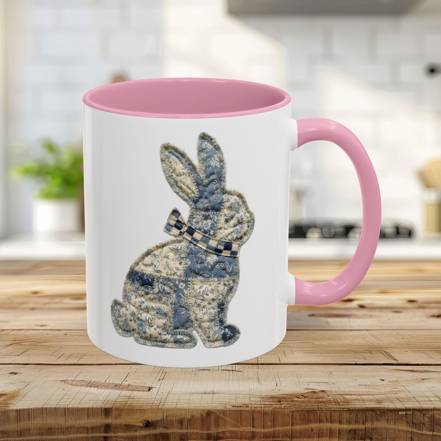 Glossy white 11oz ceramic mug with pink interior/handle and a blue patchwork bunny illustration.