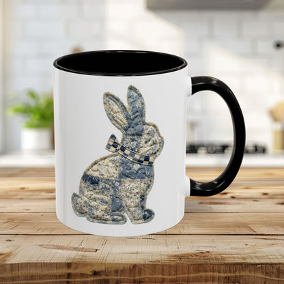 White 11oz ceramic mug with black handle and interior, featuring a blue and stone patchwork bunny illustration.