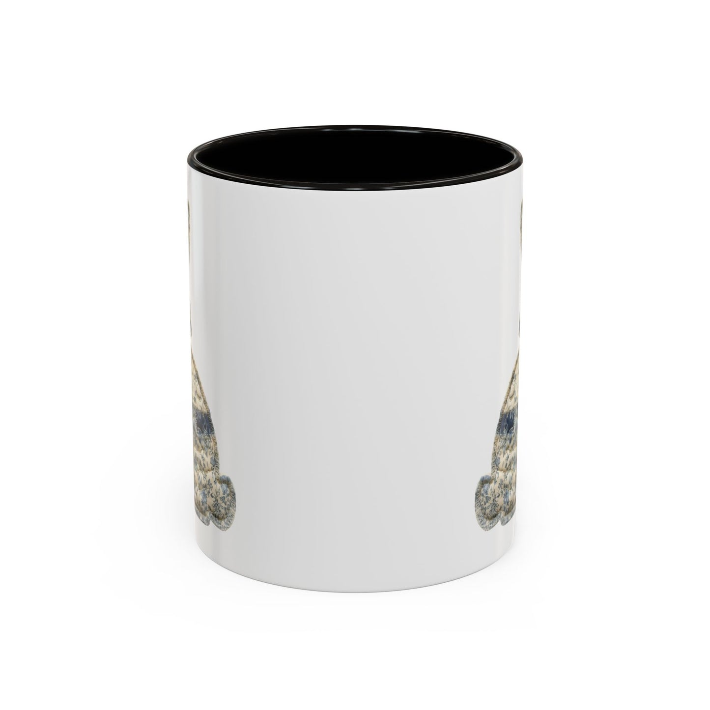 White ceramic coffee mug with black interior, featuring a partial patchwork bunny illustration in muted blues and stone tones.