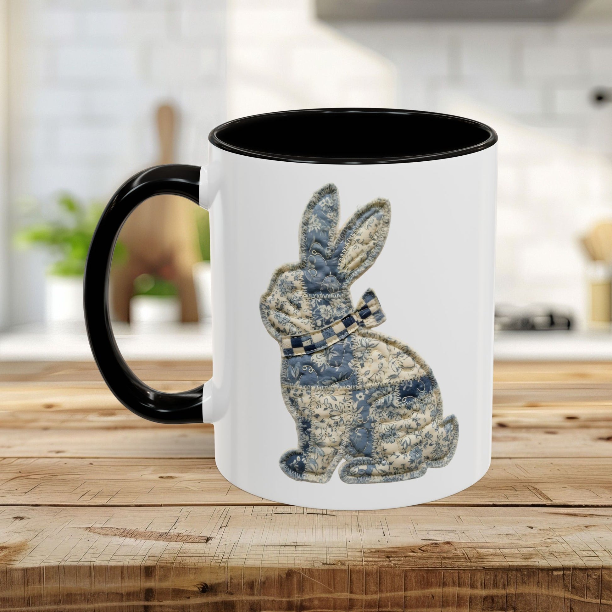 White ceramic coffee mug with black handle and interior, featuring a blue patchwork bunny illustration.