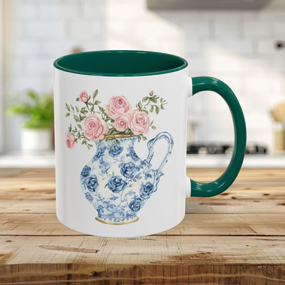 White ceramic 11oz mug with a green handle and interior, featuring a blue-and-white rose pitcher design.