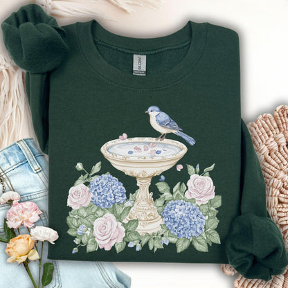Forest Green sweatshirt with a watercolor bird bath, blue bird, pink roses, and blue hydrangeas.
