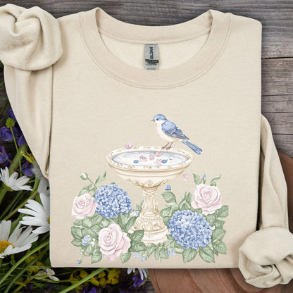 Sand sweatshirt with watercolor bird bath, blue bird, pink roses, and blue hydrangeas.
