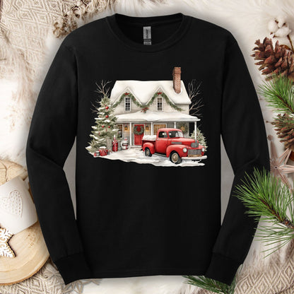 Black Gildan long sleeve tee with a watercolor farmhouse Christmas scene: red truck, snow, and evergreens.