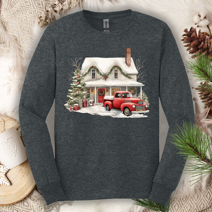 Dark Heather long-sleeve tee with a watercolor farmhouse Christmas scene: red pickup, snow, and evergreen.