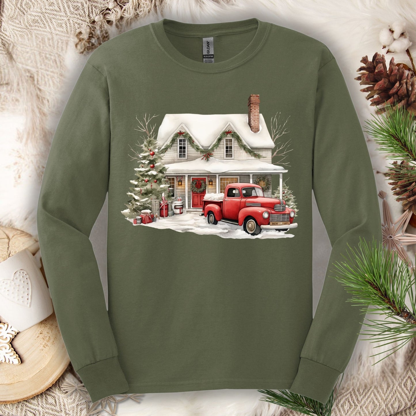 Military green long sleeve tee with a watercolor farmhouse Christmas scene and red pickup truck.