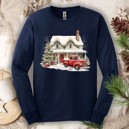 Navy long-sleeve tee with a watercolor farmhouse Christmas scene: red truck, snow, and evergreens.