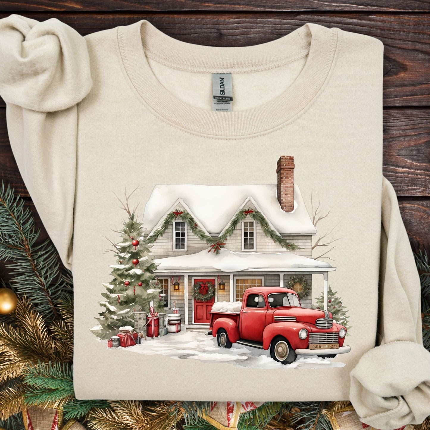 Sand Gildan sweatshirt with a watercolor farmhouse, red vintage truck, and Christmas tree in snow.