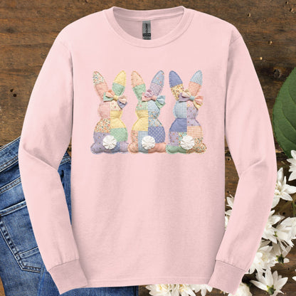 Light pink long sleeve tee with three pastel patchwork bunny tails across the chest.
