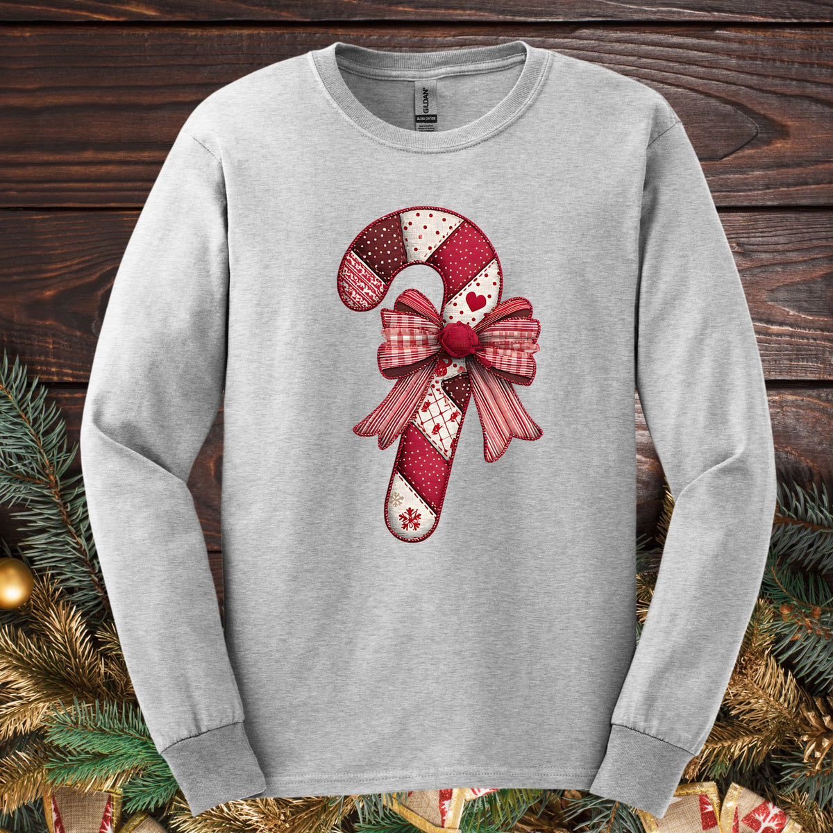 Ash Gildan long sleeve tee with a faux patchwork candy cane and red bow design.