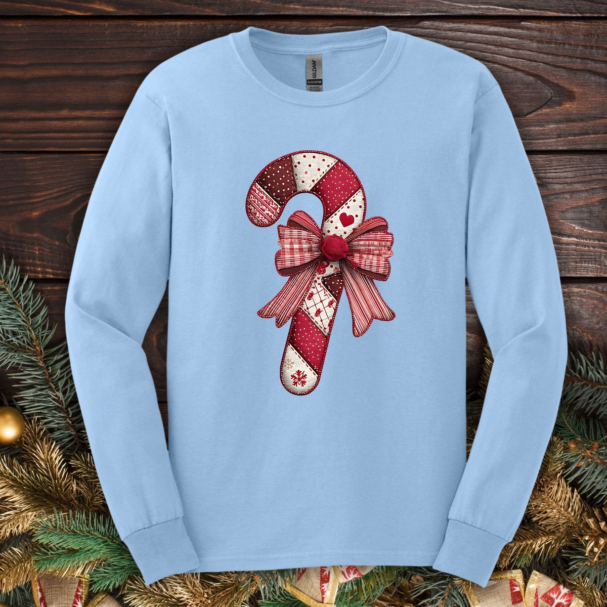 Light blue Gildan long sleeve tee with a vintage faux patchwork candy cane and red bow design.