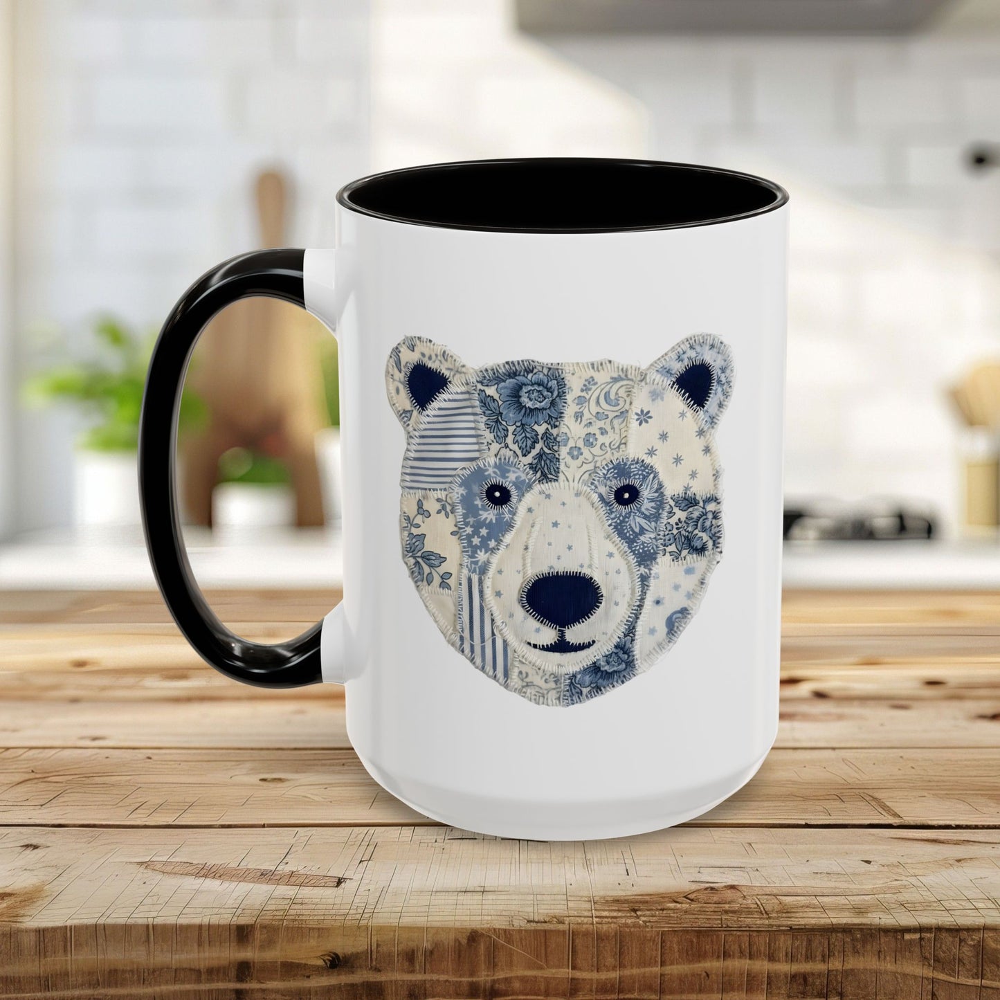 White ceramic mug with black rim and handle, featuring a blue and white faux patchwork winter bear face.
