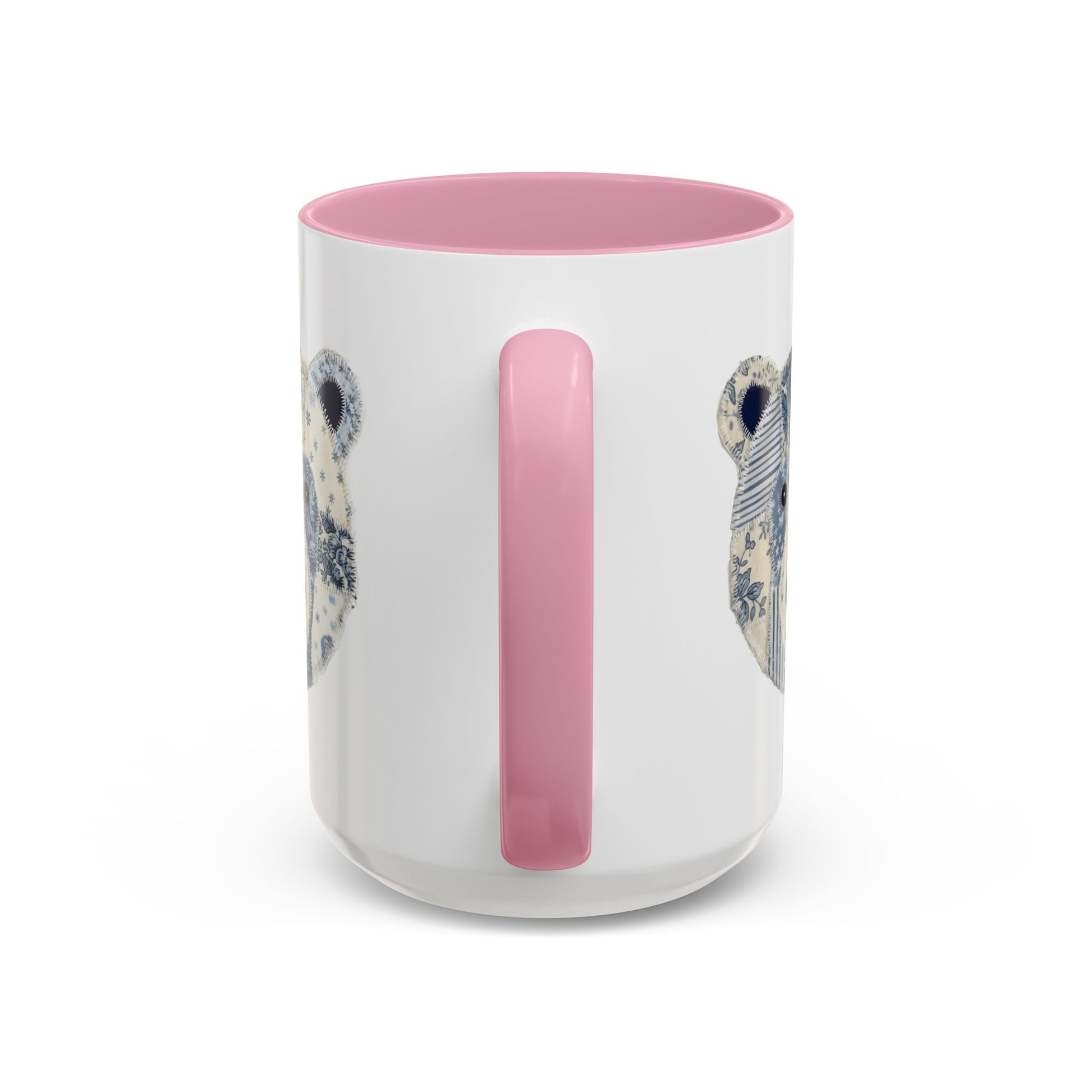 White ceramic mug with pink rim and handle, featuring a blue and white faux patchwork winter bear design.