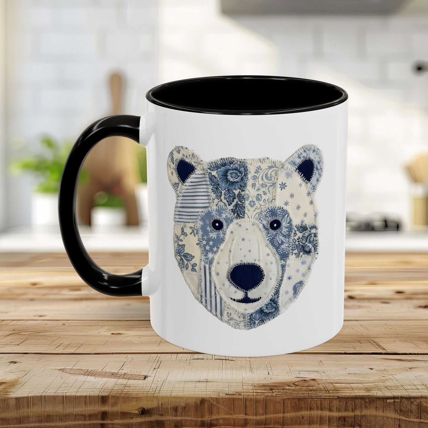 White ceramic mug with black rim and handle, featuring a blue and white faux patchwork winter bear face.