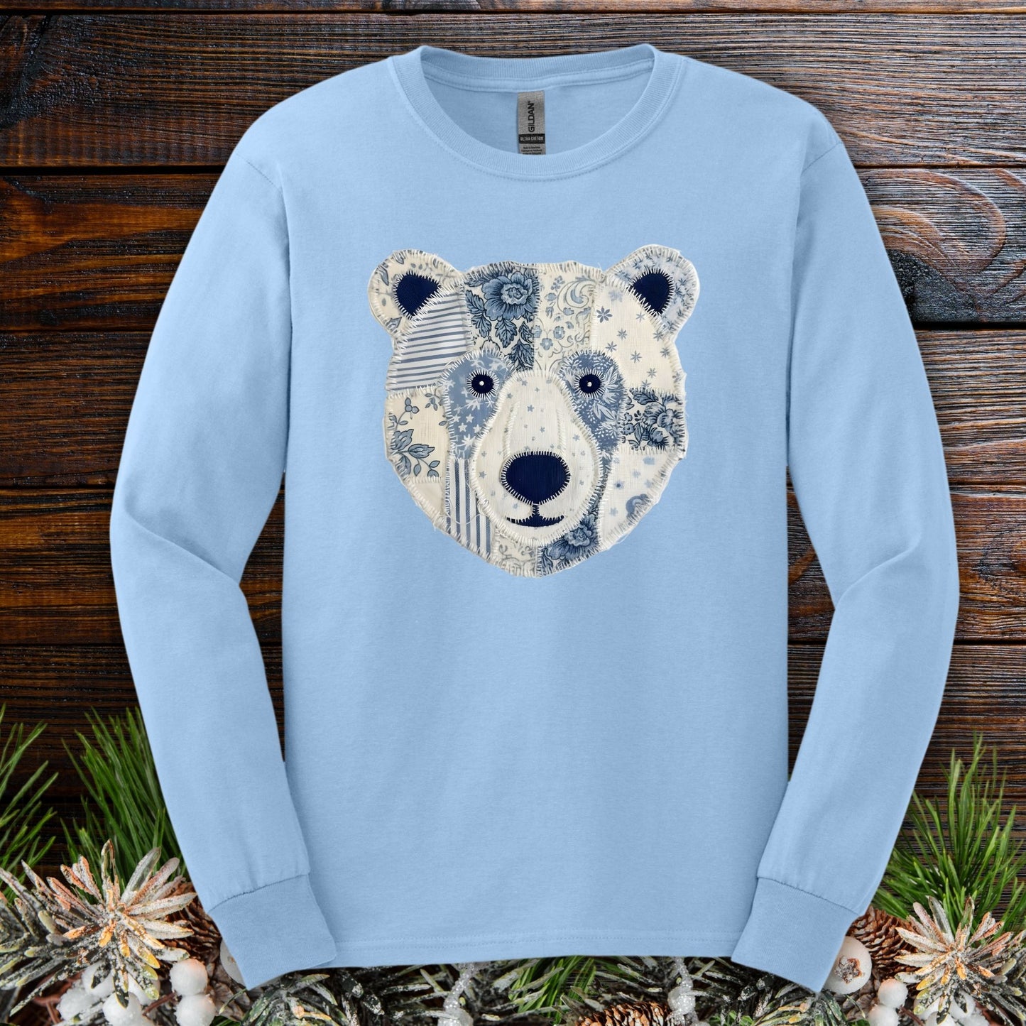 Light blue long sleeve tee with a faux patchwork winter bear face design.
