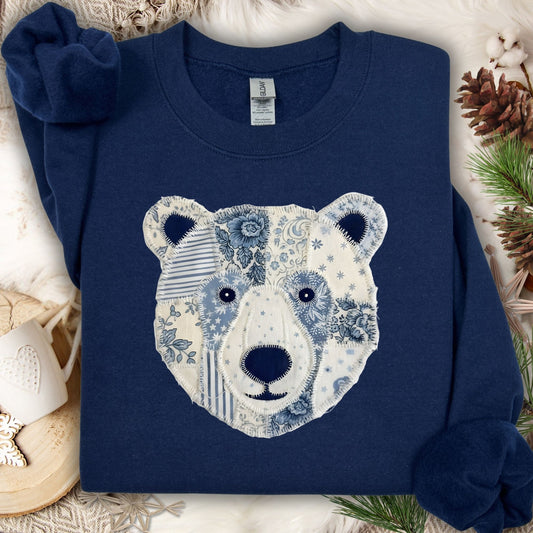 Navy blue sweatshirt with a faux patchwork country winter bear design in blue and white patterns.