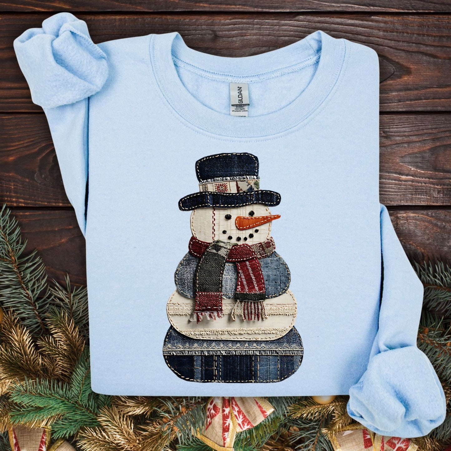 Light blue Gildan sweatshirt with a printed faux patchwork denim snowman design.