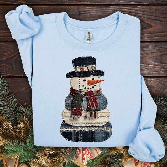 Light blue Gildan sweatshirt with a printed faux patchwork denim snowman design.