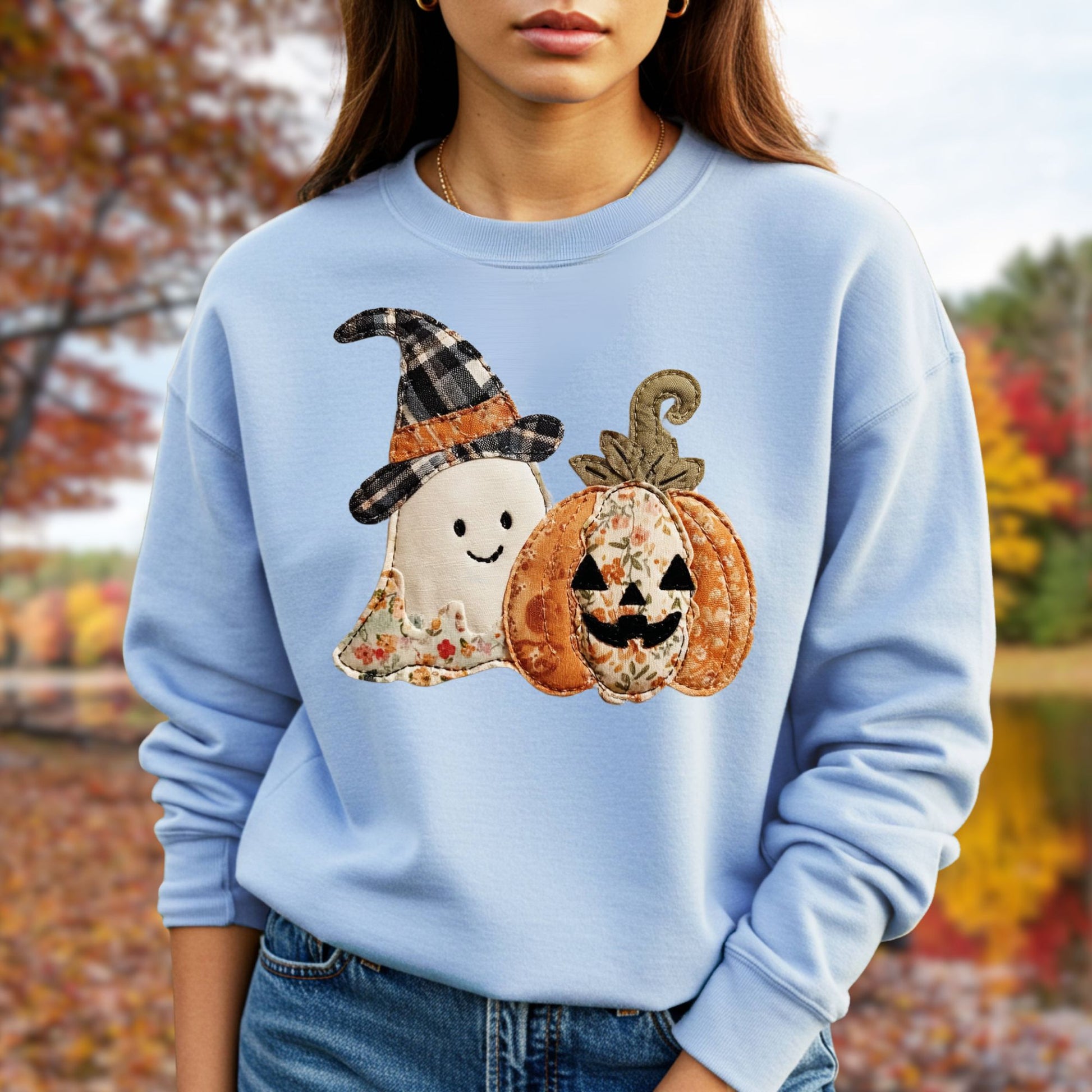 Light blue crewneck sweatshirt with a faux patchwork ghost in a plaid witch hat and a floral jack-o-lantern.