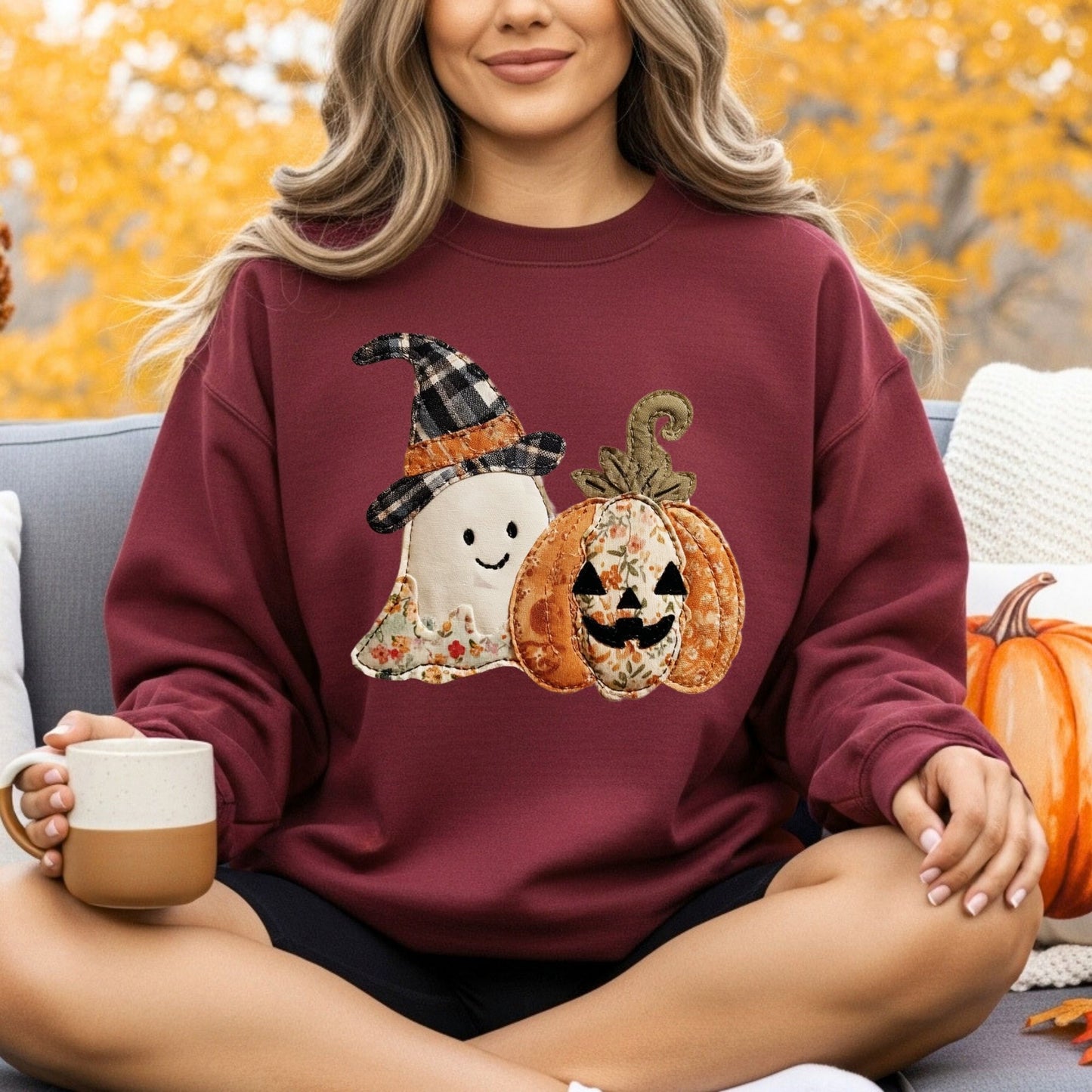 Woman in a maroon Gildan sweatshirt with a faux patchwork ghost in a plaid witch hat and a floral jack-o-lantern.