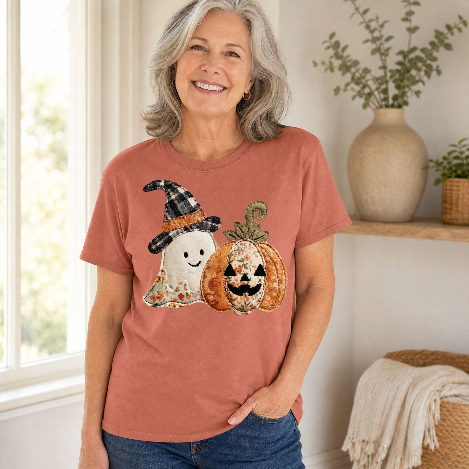 Woman in a rust Comfort Colors t-shirt with a faux patchwork ghost in a witch hat and a floral jack o'lantern.