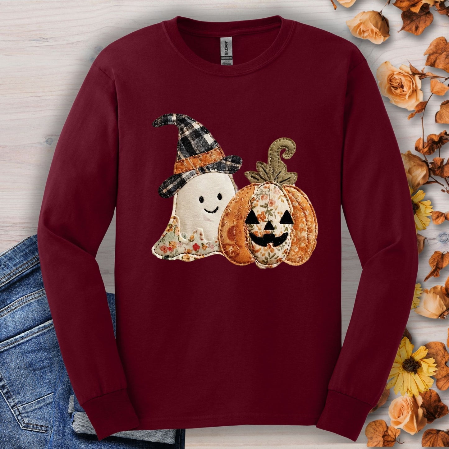 Maroon long sleeve tee with a faux patchwork ghost in a plaid hat and a floral pumpkin.