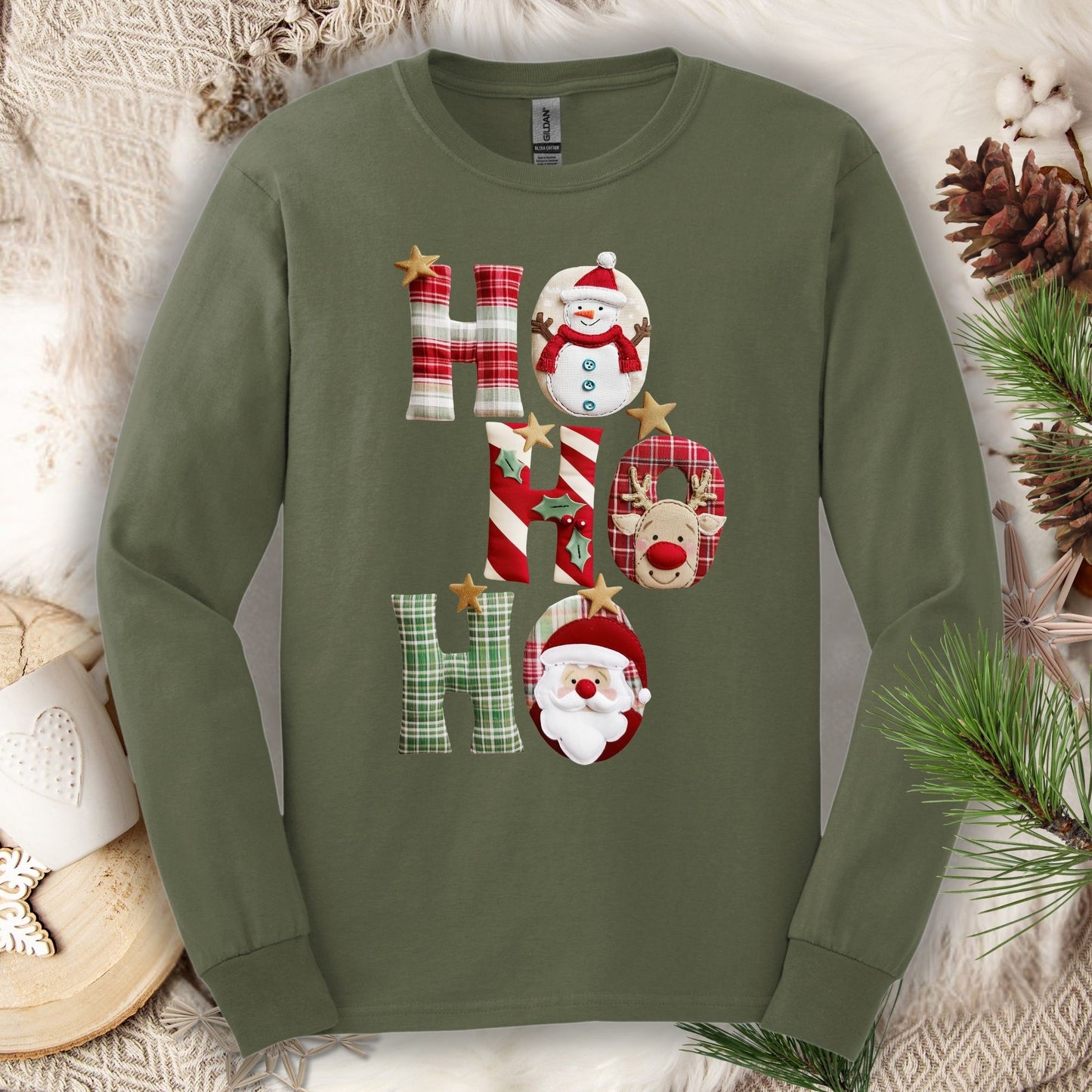 Military green 100% cotton long sleeve tee with a faux patchwork "Ho Ho Ho" design featuring Santa, Rudolph, and a snowman.