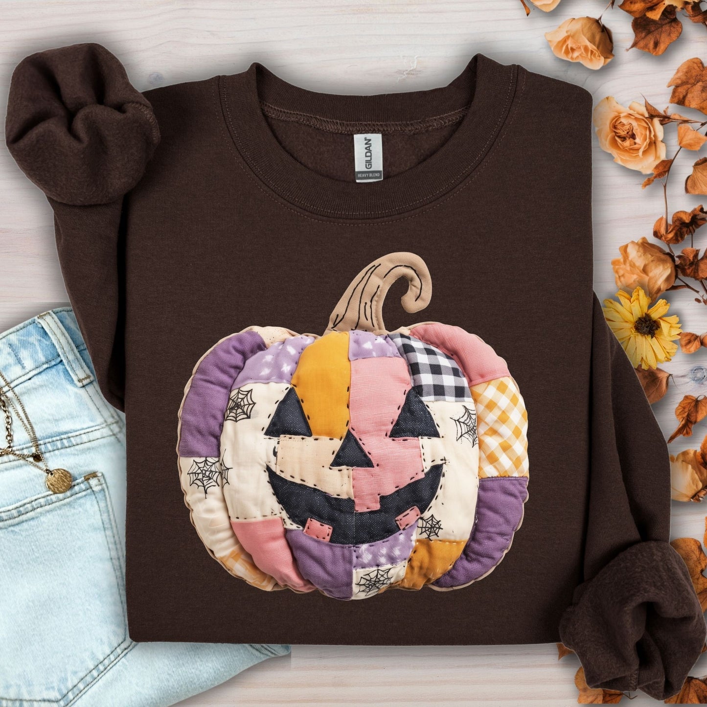Dark Chocolate Gildan sweatshirt with a quilted patchwork jack-o-lantern in pink, purple, and yellow tones.
