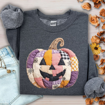 Dark Heather Gildan sweatshirt with a pink, purple, and yellow faux patchwork jack-o-lantern design.