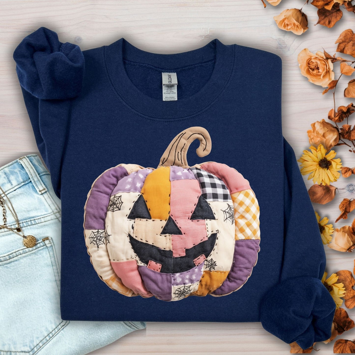 Navy Gildan sweatshirt with a pink and purple faux patchwork jack-o-lantern design.