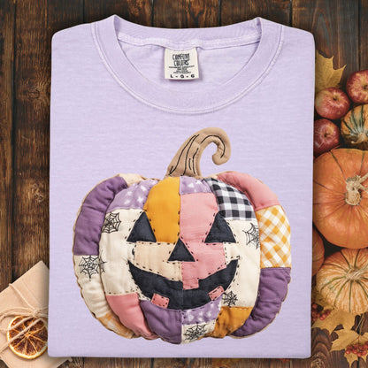Orchid Comfort Colors tee with a whimsical faux patchwork jack-o'-lantern in pink, purple, and orange tones.