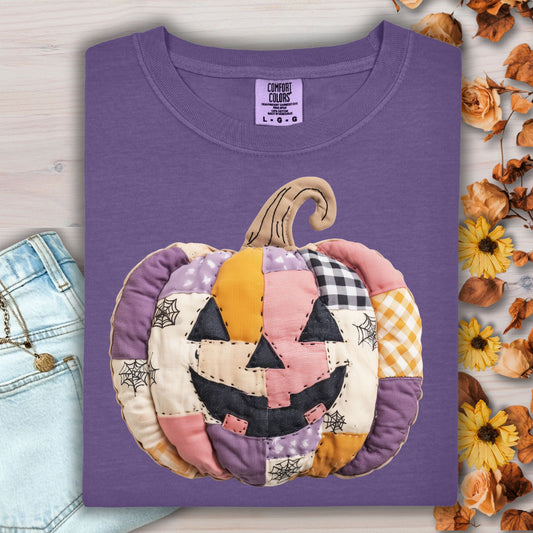 Grape Comfort Colors tee with a whimsical faux patchwork jack-o'-lantern in pink, purple, and orange tones.