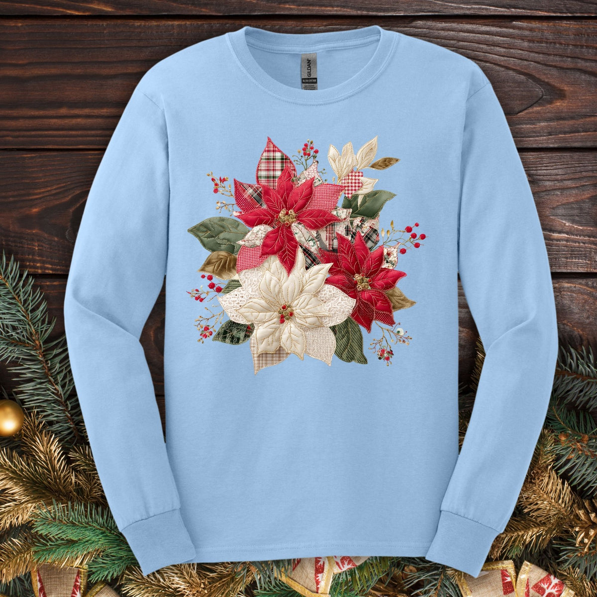 Light blue Gildan long sleeve tee with a faux patchwork poinsettia design featuring red, white, gingham, and plaid.