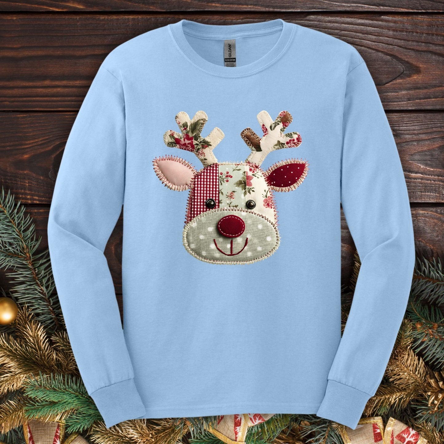 Light blue Gildan long sleeve tee with a faux patchwork Rudolph design in sage green and deep red.