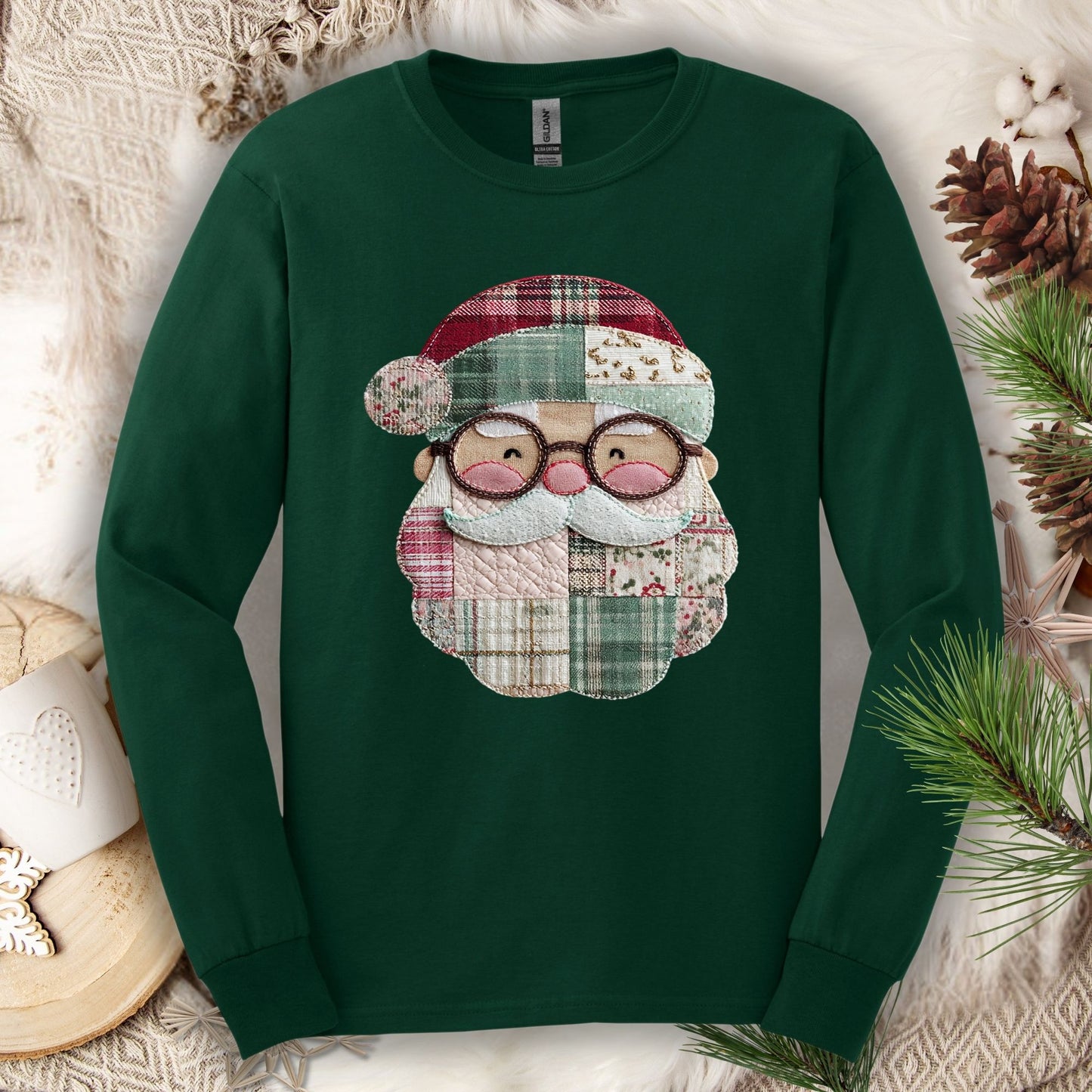Forest green long sleeve tee with a printed faux patchwork Santa face in red, cream, and green.