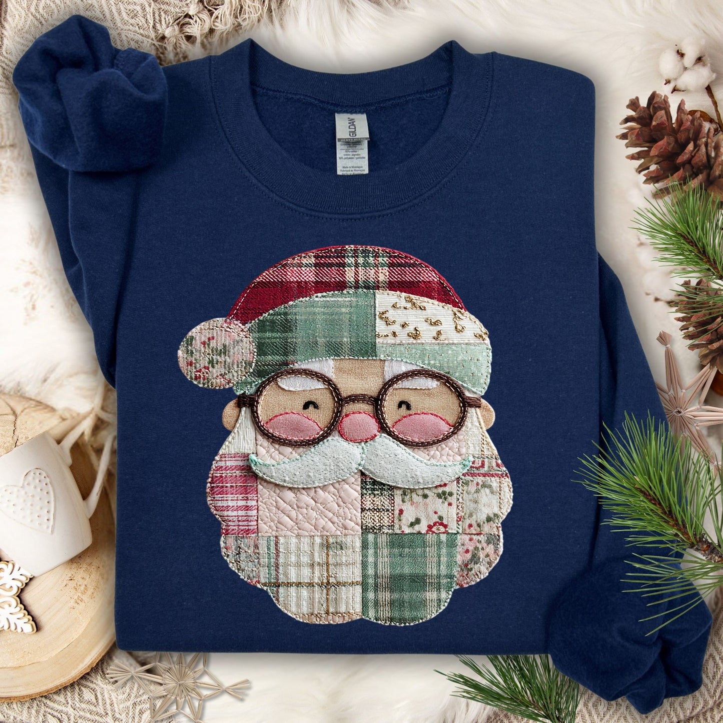 Navy Gildan sweatshirt with a printed faux patchwork Santa face, surrounded by pinecones and greenery.