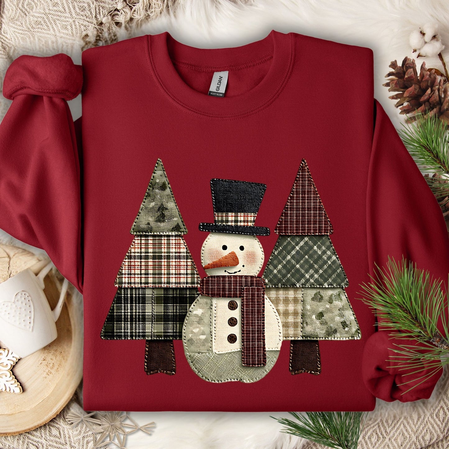Cardinal Red Gildan sweatshirt with a faux patchwork snowman and evergreen trees in earth tones.
