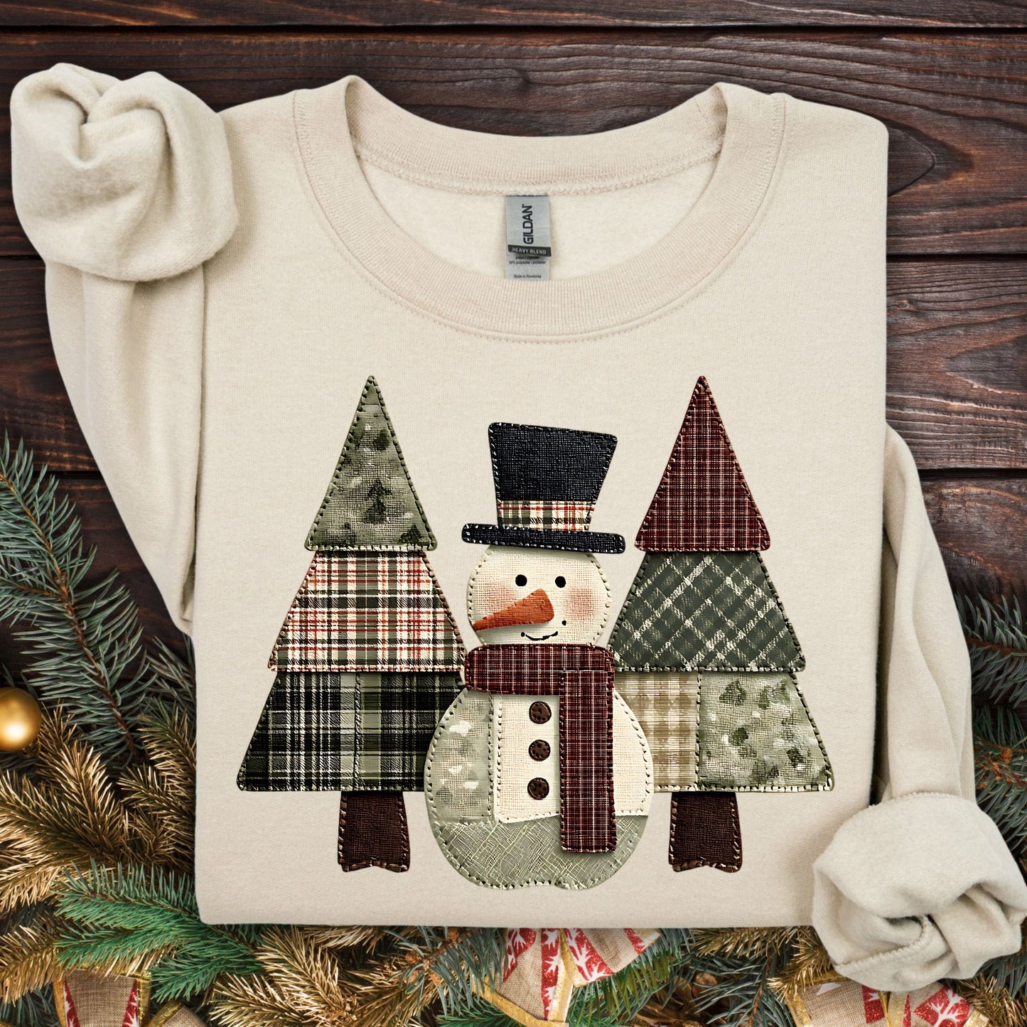 Sand Gildan sweatshirt with a printed faux patchwork snowman and evergreen trees.