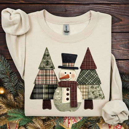 Sand Gildan sweatshirt with a printed faux patchwork snowman and evergreen trees.
