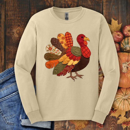 Sand long sleeve tee with a colorful faux patchwork quilted turkey design in red, gold, brown, and forest green.