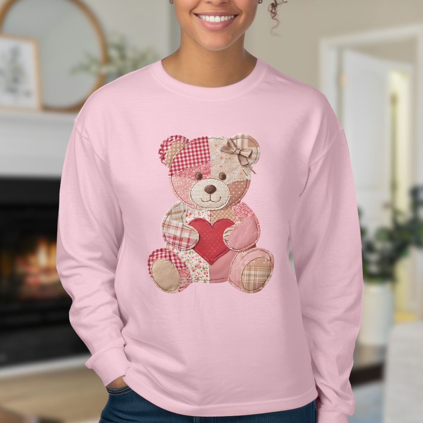 Pink long-sleeve tee with a faux patchwork teddy bear holding a red heart.