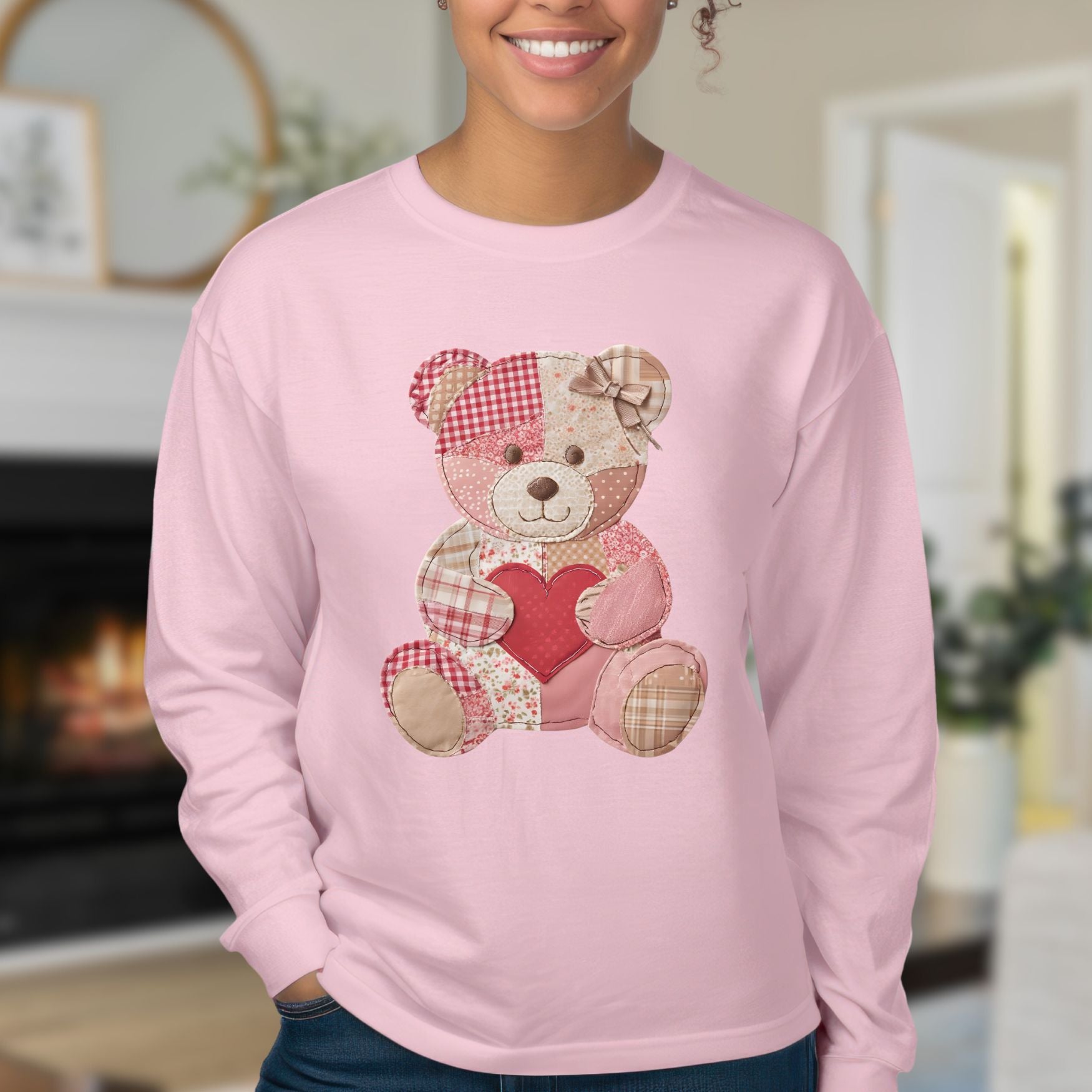 Pink long-sleeve tee with a faux patchwork teddy bear holding a red heart.