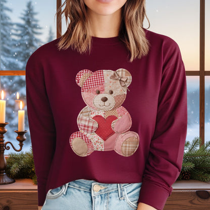 Woman in a burgundy long-sleeve tee with a faux patchwork teddy bear holding a red heart.