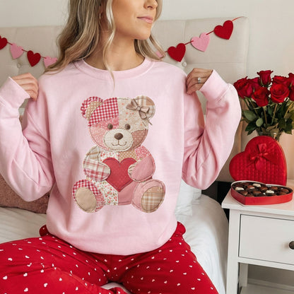 Pink crewneck sweatshirt with a vintage patchwork teddy bear holding a red heart.
