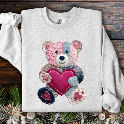 Ash gray sweatshirt with a faux patchwork teddy bear holding a pink heart.