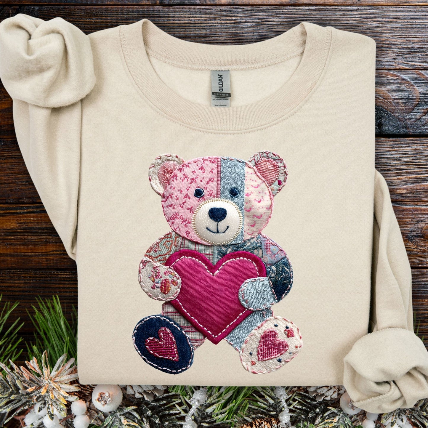 Sand crewneck sweatshirt with printed faux patchwork teddy bear holding a pink heart.