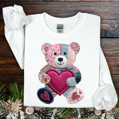 White Faux Patchwork Valentine's Teddy Bear Sweatshirt with a pink heart, on a rustic wood background.