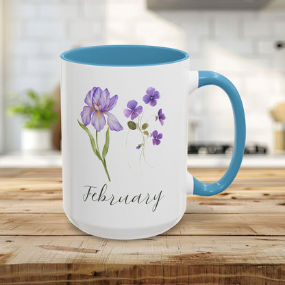 White ceramic 15oz mug with light blue interior and handle, featuring watercolor purple iris and violet flowers and "February".