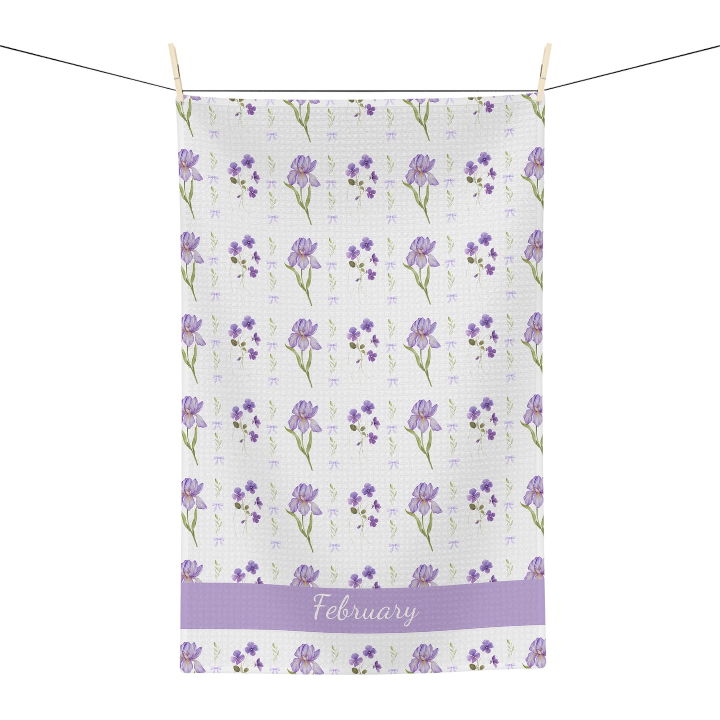 White microfiber tea towel with purple irises, violets, and "February" text, hanging on a line.