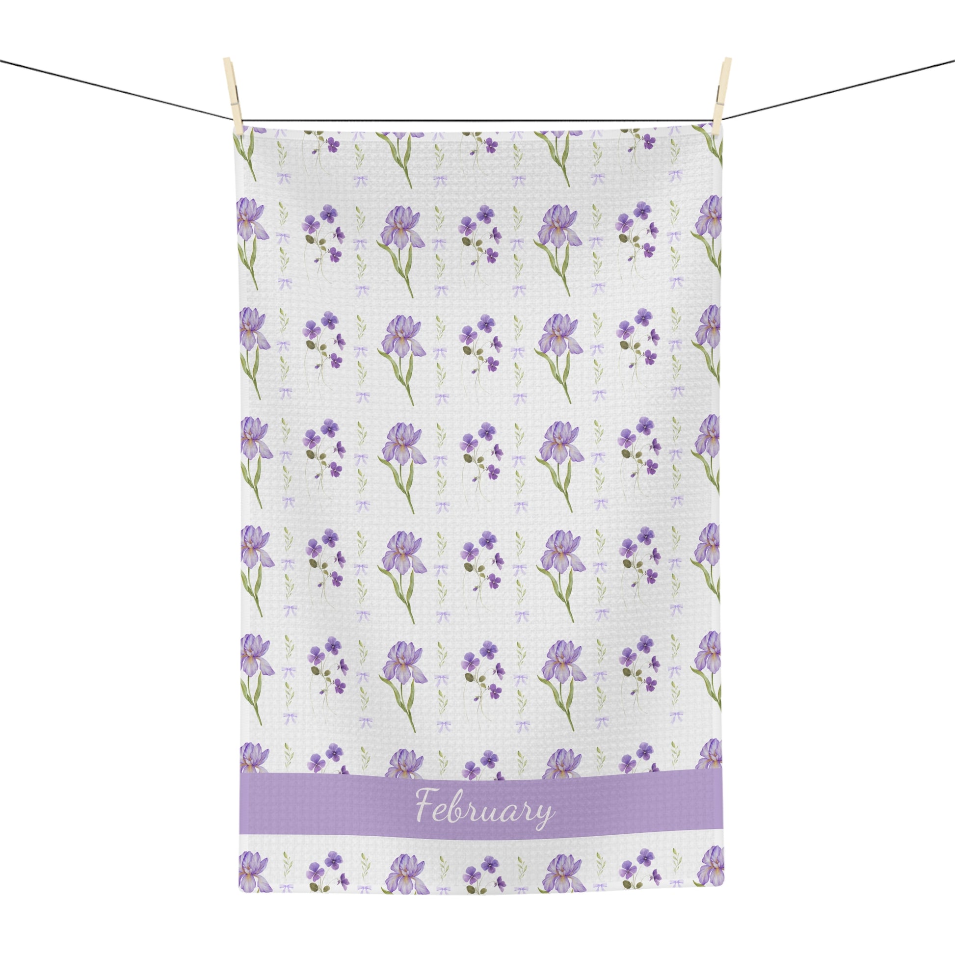 White microfiber tea towel with purple irises, violets, and "February" text, hanging on a line.